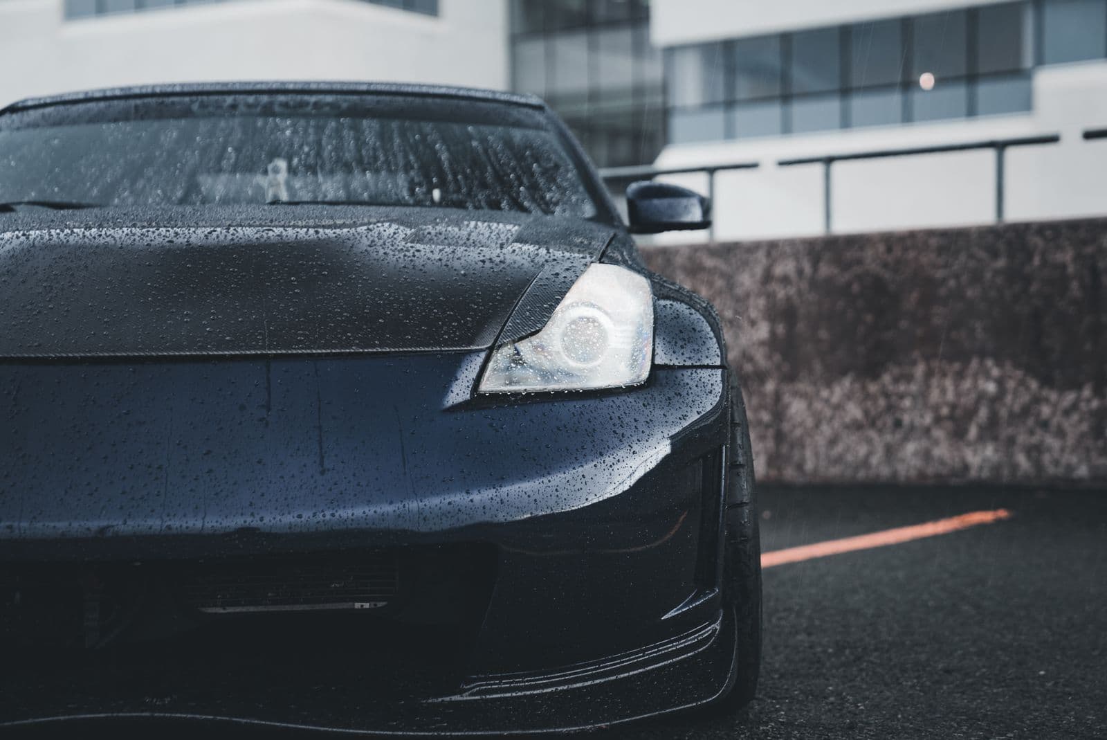 Rain beading on the freshly finished hood of a black sports car